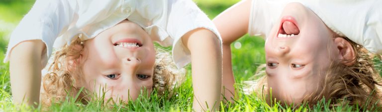 Two children smiling while lying on grass