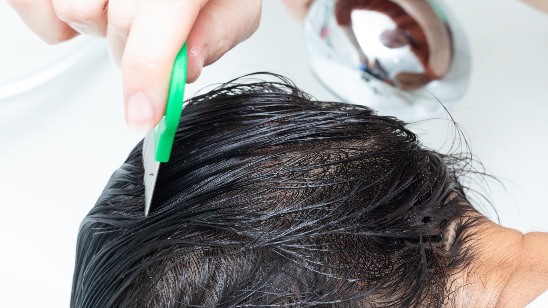 Fine-tooth comb moving through wet hair during lice treatment