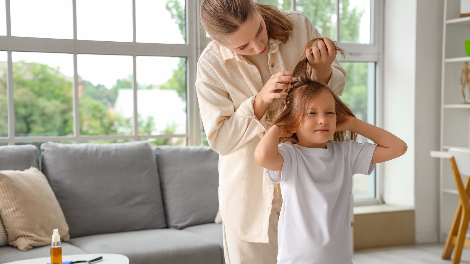 A calm parent in Mercer County checking a young child's hair by hand under bright light, section by section, for lice and nits
