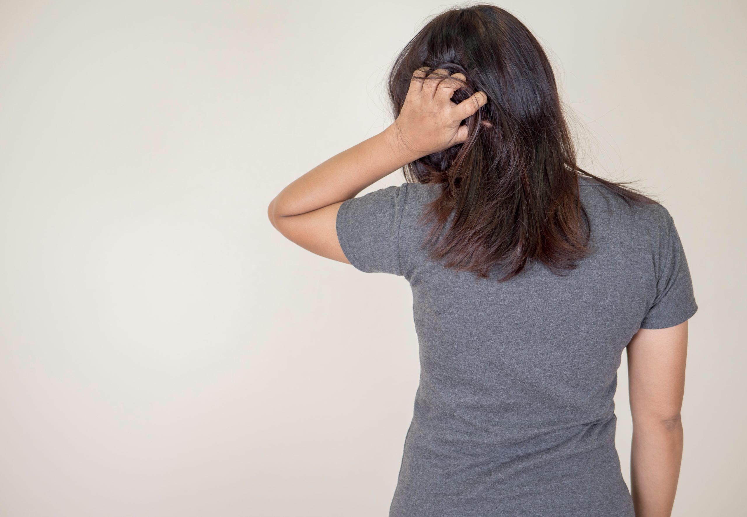 Adult woman scratching her scalp as a possible sign of head lice
