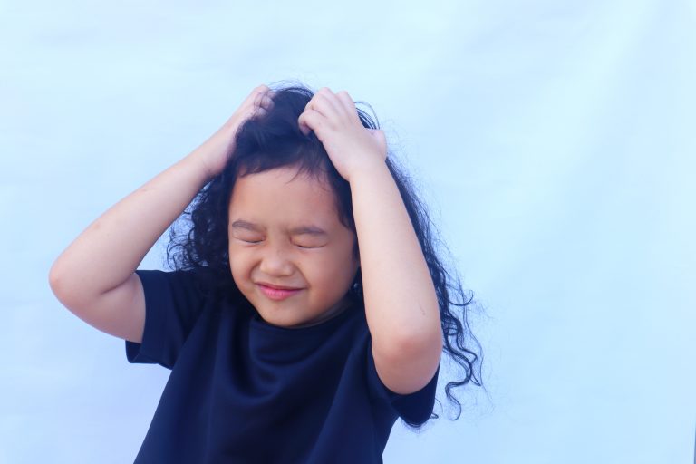 Child scratching their head with both hands
