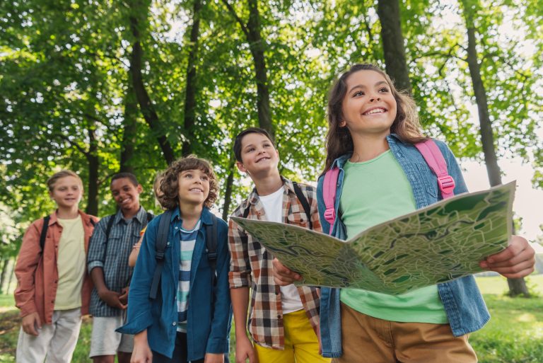 Group with backpacks standing among trees while one person holds an open map.