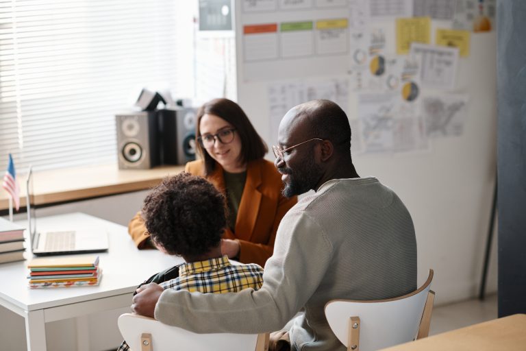 Child and two adults meeting at a classroom desk